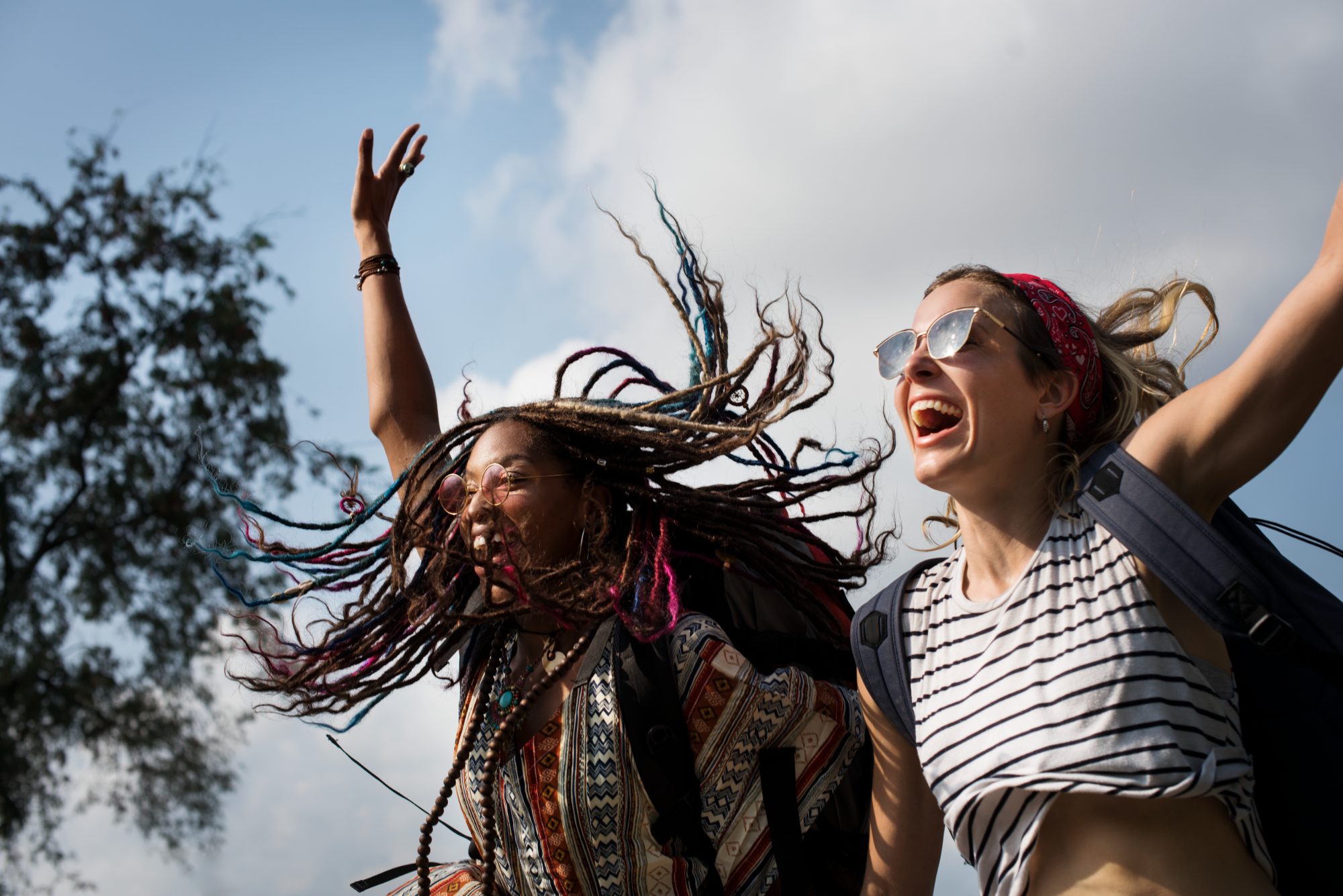 Amigos comemorando de braços erguidos ao ar livre em um festival